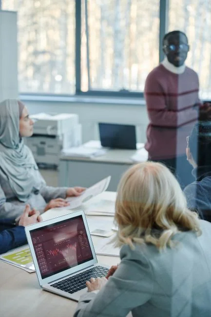 Vue plongeante d’une équipe diversifiée examinant des stratégies marketing à l’aide de tableaux et de graphiques.